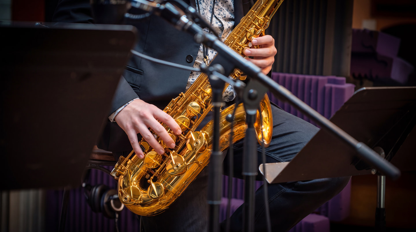 A saxophonist’s hands playing a golden saxophone on stage