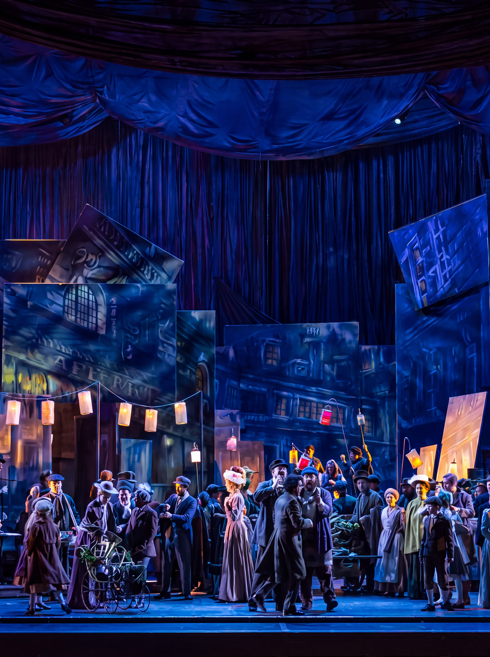 An opera ensemble performing on a blue-lit stage