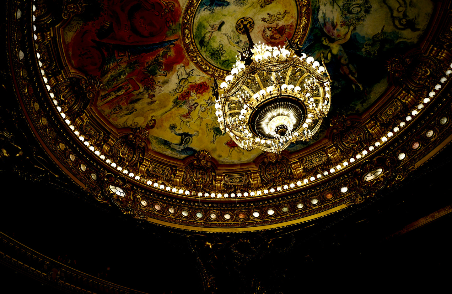 An ornate opera-house chandelier beneath a painted ceiling