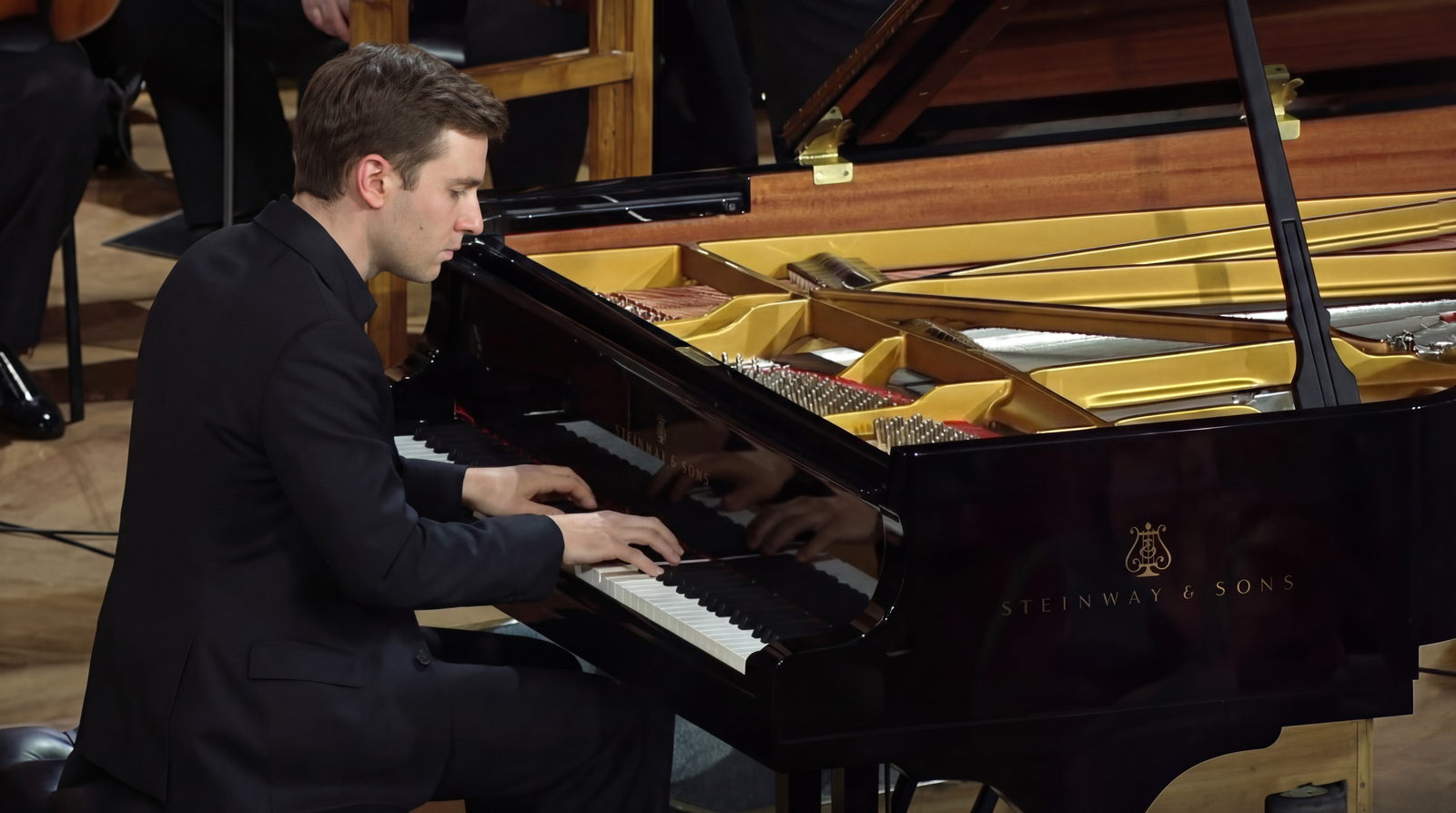 A pianist at a Steinway concert grand in a wood-panelled hall