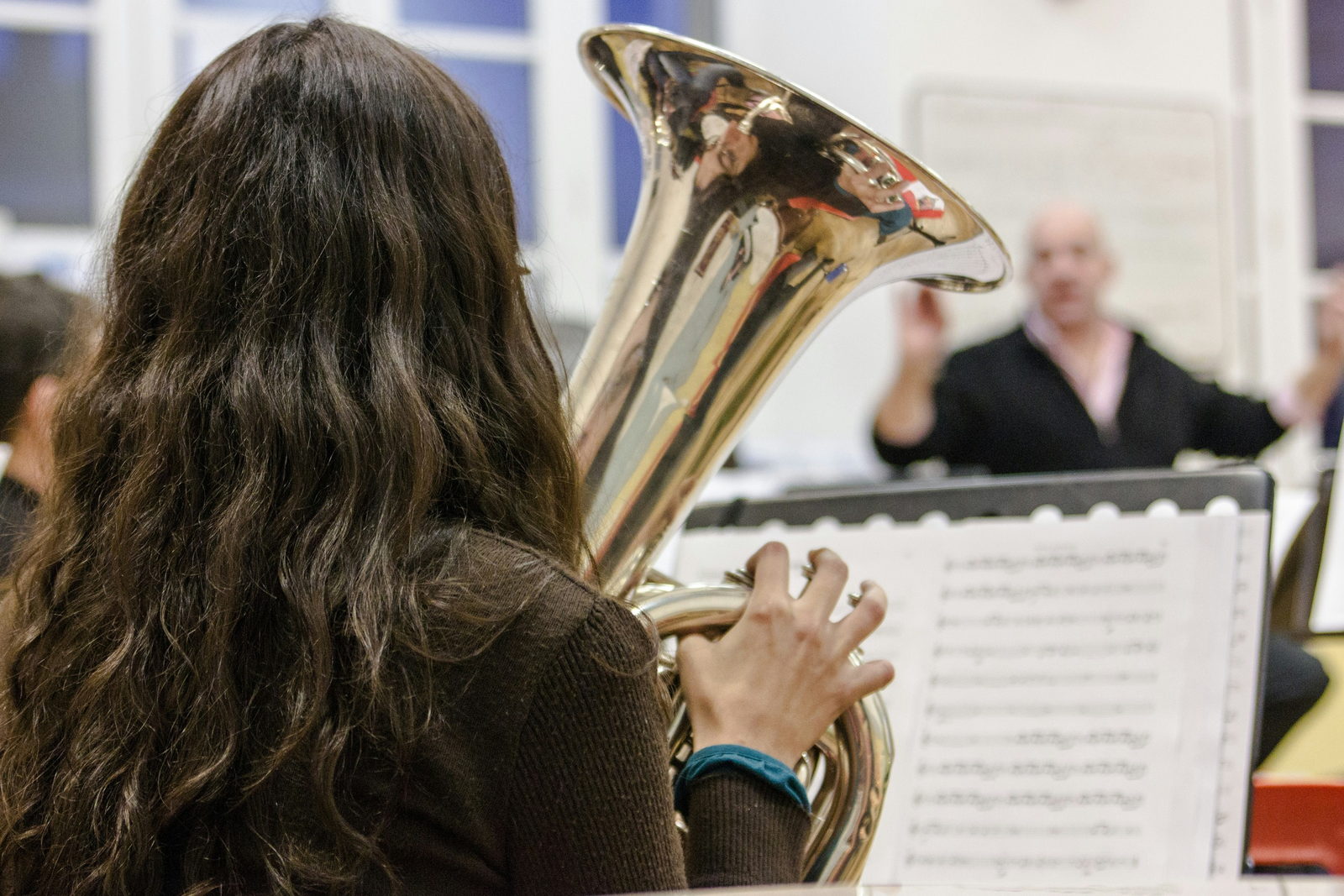A young tuba player following a conductor in rehearsal